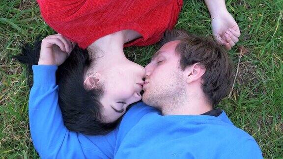 浪漫的年轻情侣躺在草地上接吻爱情浪漫吸引力
