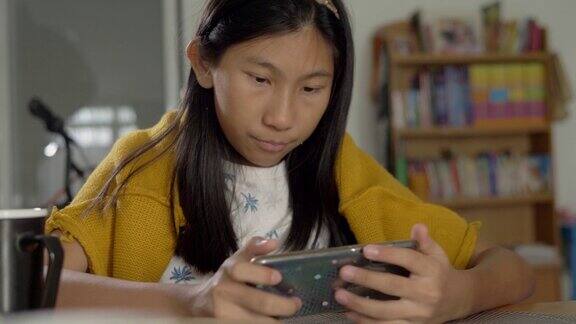 亚洲女孩穿着黄色毛衣坐在家里的椅子上看病毒视频生活方式概念