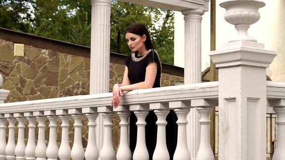 优雅的女孩倚在阳台的旧栏杆上