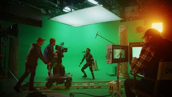 在大电影制片厂专业摄制组拍摄大片导演命令摄像机操作员开始拍摄绿色屏幕CGI场景与演员穿着运动跟踪服和头部钻机