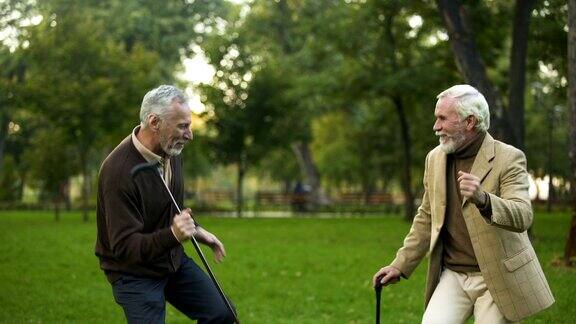 男性退休老人在公园跳舞拄着拐杖友谊幽默开心