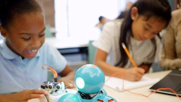 兴奋的STEM(科学、技术、工程、数学)小学生在技术课上测试机器人