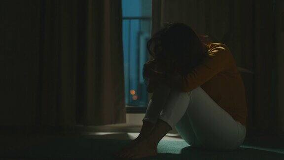 一个抑郁的女人独自坐在公寓房间的地板上