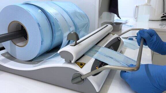 牙医助理戴上手套用真空包装机将用于高压灭菌的牙科器械装在塑料袋内无菌安全护理理念
