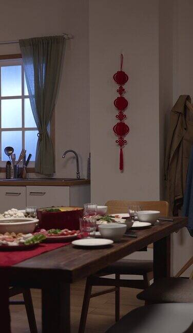 竖屏:温馨的家庭内部贴着春联餐桌上摆放着庆祝中国农历新年的食物门上和墙上的字翻译:春天和祝贺