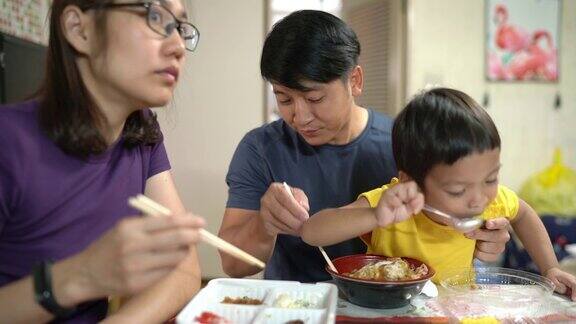 亚洲男孩和他的爸爸妈妈一起吃日本烧日本蛋