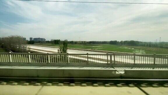 在火车上看着窗外经过城市郊区的公路和农场运河