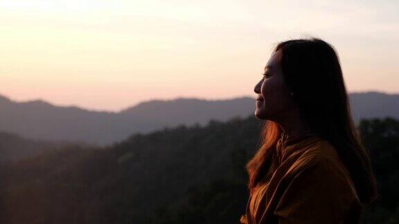 一个女性旅行者坐在山顶上的特写在早上看日出