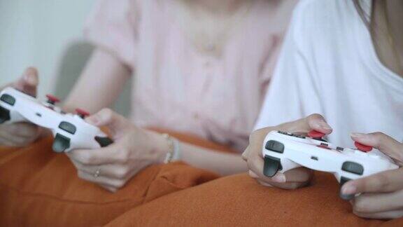 年轻的亚洲女性在家里用操纵杆一起玩电子游戏的慢动作场景