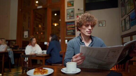 清晨一名男子坐在当地的咖啡馆里看报纸