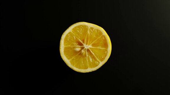 顶部视图:一半柠檬旋转在一个黑色表面-停止运动