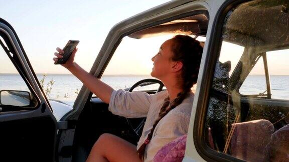 假日照片美丽的女孩在背景海的古董车上做手机自拍照片快乐的女性在车做自拍