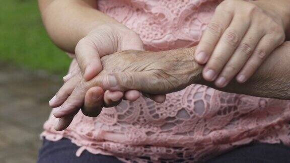 护理人员按摩痛风肿痛的老年妇女的手指和手腕