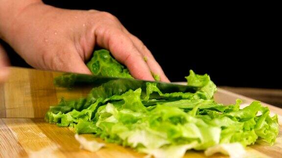 切好的绿色沙拉叶子在切菜板上的特写
