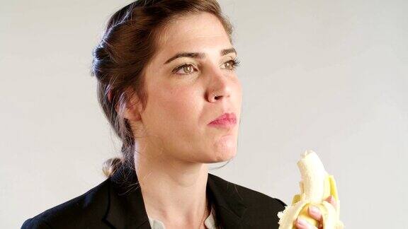 一个女人吃香蕉的特写在一个白色的工作室背景