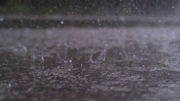 慢镜头特写:雨滴落在街道上形成一个大水坑