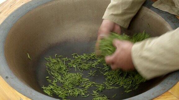 农场工人用中国传统的方式在钢锅里炒茶