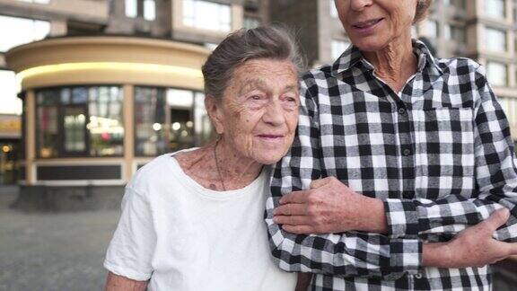 照顾老人的护士志愿护士拥抱老年妇女微笑开心走在院子里公寓、养老院、帮助老人成熟的女儿去看望奶奶