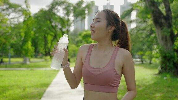 一名亚洲妇女在公园里锻炼她正在喝水解渴