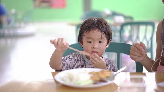 亚洲男孩在操场上玩耍后吃着米饭煎蛋卷