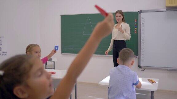 初中女老师在课堂上画几何图形给坐在课桌上的小学生