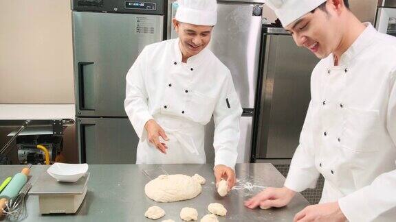 身着制服的亚洲男厨师正准备在一个不锈钢厨房里烤面包