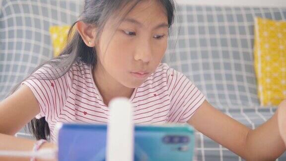 2019冠状病毒病期间亚洲女孩使用智能手机在家学习在家接受教育