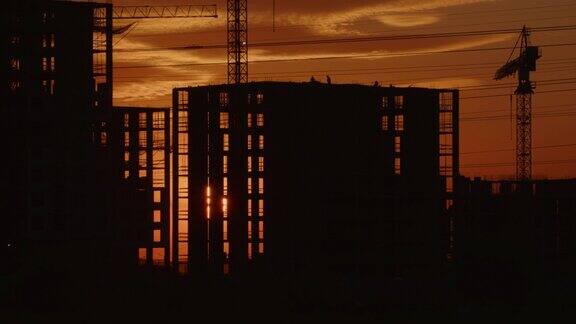 时光流逝大太阳落在正在施工的建筑后面阳光透过多层住宅的窗户