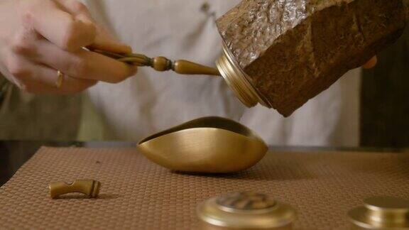 师傅用手将干茶从铜罐倒入茶海准备制茶