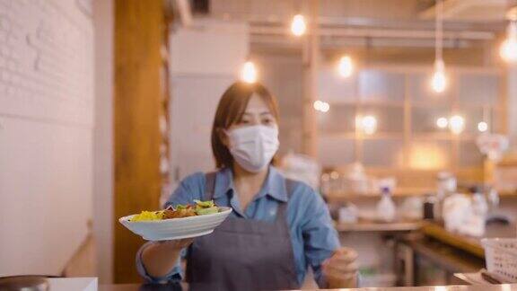 女厨师在café和餐厅的商业厨房给女服务员递食物