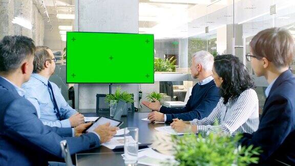 各种各样的成功商业人士在会议室绿屏彩色钥匙电视在墙上他们关注公司的成长分享图表和统计数据