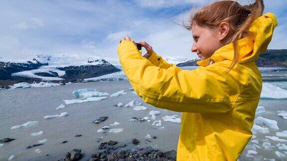 在一个刮风的日子里一名妇女在冰川泻湖上拍摄漂浮的冰山