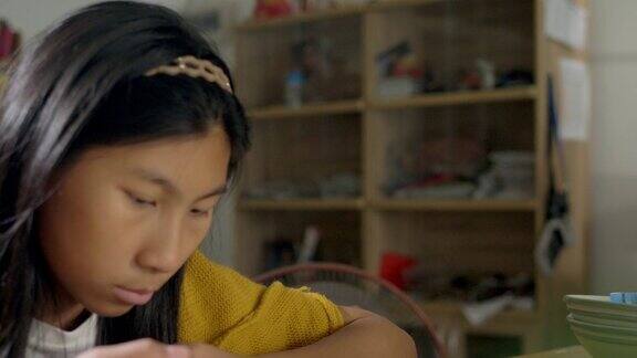 亚洲女孩穿着黄色毛衣坐在家里的椅子上看病毒视频生活方式概念