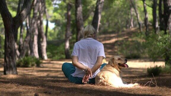 一个女人在森林里和她的狗练习瑜伽