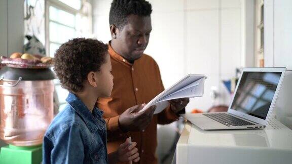父亲和儿子在家里用笔记本电脑在线学习