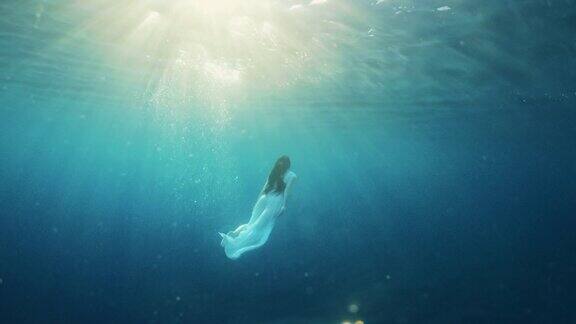 穿着白色连衣裙的女子在水下游泳