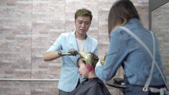 亚洲华人和印度理发师在美容院染发女顾客的头发