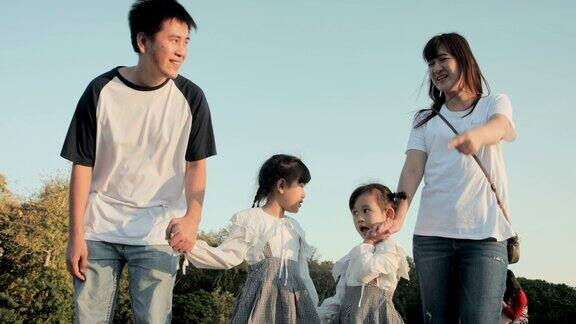日落时分亚洲家庭带着年幼的孩子在公园里散步和跑步