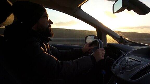 司机一个英俊的年轻人开着一辆车车上装有GoPro相机拍摄在日落时分开车