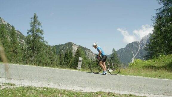 慢镜头:被陡峭的山路打败骑自行车的人沿着自行车走