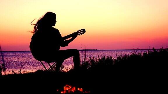 日落时分小女孩在海滩上弹吉他