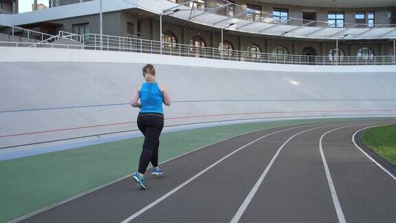超重女性在城市体育场跑道上慢跑
