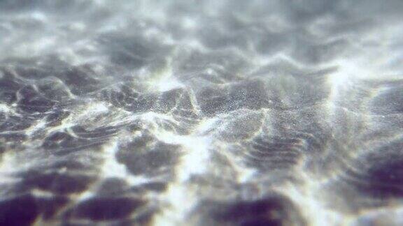 水下白色沙质海底水波搅动着白色的沙子一片沙滩阳光穿过海洋抽象背景慢动作无缝循环
