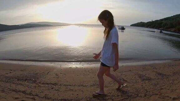 女孩在日落希腊的沙滩上玩