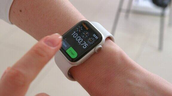 Smartwatch年轻女子使用智能手表女性触屏进入手表应用的特写