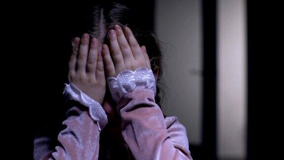 小女孩害怕用手掌捂着脸害怕鬼的恐惧症概念