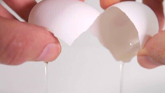 一个鸡蛋在手中被打碎并倒出来的极端特写镜头