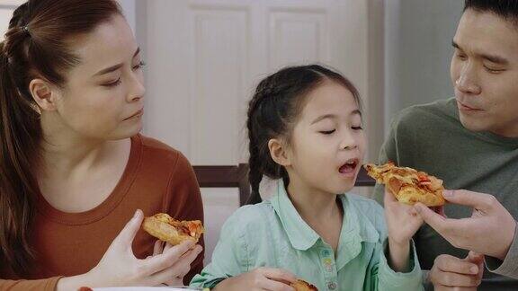 亚洲人喜欢在家吃美味的披萨父母和女儿吃着外卖的美味意大利菜概念食品外卖