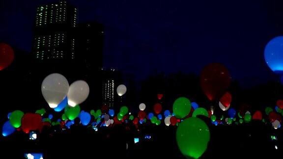 爱的盛宴在夜晚城市的天空中飞行的彩色氦气发光的气球