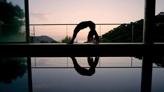保持轮子姿势的平衡在泳池边做瑜伽的女人